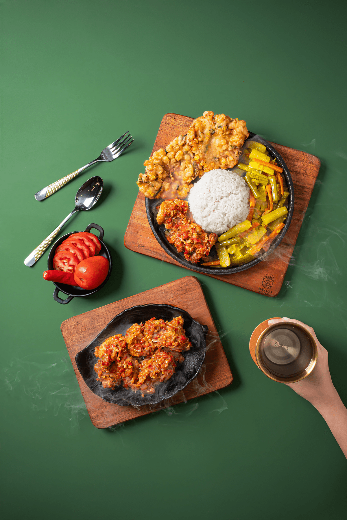 The set from above: rice, fried chicken, vegetables and a hot plate on wooden boards, cutlery to the side