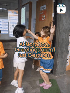 Feed tile, reel: At Morphoo, greetings aren't just gestures. Two children greeting each other at the door of Primary 2A